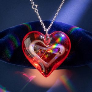A red lampwork glass heart pendant with a white and gold swirl inside