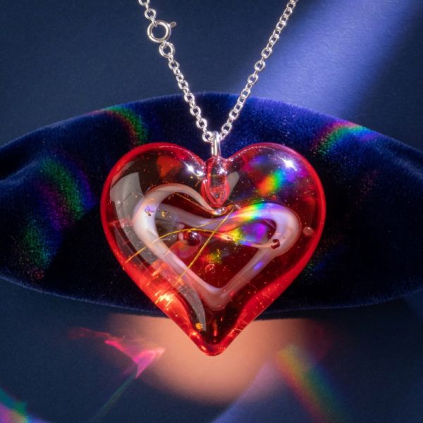 A red lampwork glass heart pendant with a white and gold swirl inside